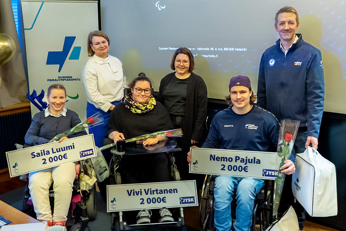 Stipendiaatit stipendishekkeineen palkitsemistilaisuudessa screenin edessä.